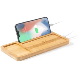 A bamboo charging organiser with cable slots and a smartphone on it, displaying charging status.