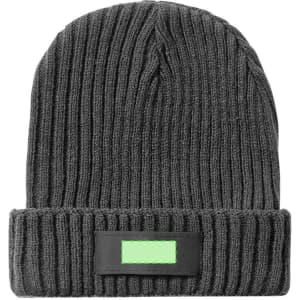 A grey beanie hat with a ribbed texture and a dark rectangular patch. It features a logo or branding.