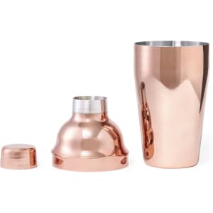A cocktail shaker set in a shiny copper finish, comprising a main shaker, a lid, and a smaller cap.