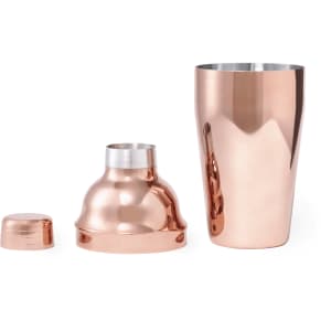 A copper cocktail shaker with a lid and a bottom section, featuring a reflective surface and sleek design.