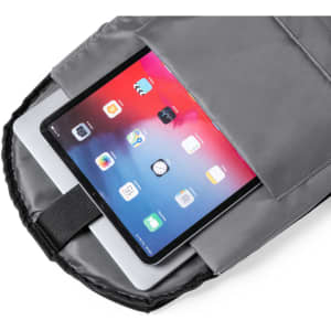 A grey anti-theft backpack with a tablet and a laptop visible inside its interior compartment.