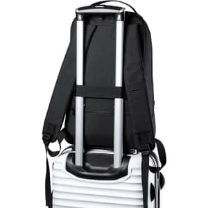 A black backpack with shoulder straps is resting on a suitcase, featuring a retractable handle.