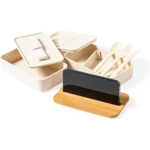 A cream-coloured lunch box set with utensils and a bamboo phone holder. It includes multiple compartments for food storage.