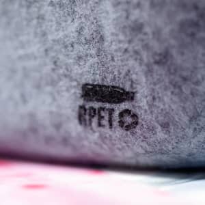 A grey pencil case made from RPET material, featuring a logo. It has a soft, felt texture.
