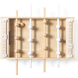 A mini table football game featuring wooden rods, white and natural wood players, set in a light wooden frame.