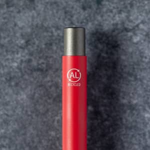 A red metal pen featuring a grey metal tip and an emblem indicating it is made from recycled materials.