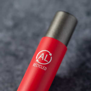 A red metal pen with a recycled logo on its barrel, featuring a black cap.