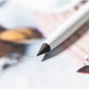 A white stylus pen with a pointed black tip rests on a colourful printed surface. It features a logo.