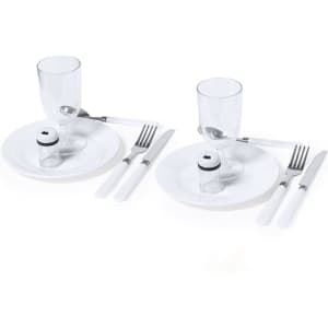 Two sets of white dinner plates with cutlery, clear glasses, and small salt shakers, all on a plain background.