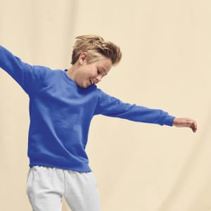 A blue kids sweatshirt with a crew neck, displayed on a smiling child wearing grey pants.