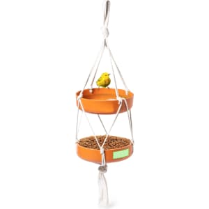 A hanging bird feeder in orange with two circular feeding trays and a decorative yellow bird on top. It features a rope design.