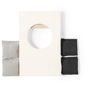 A Tumble Game featuring a rectangular wooden board with a circular hole and four bean bags in grey and black.