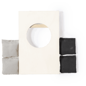 A wooden game board with a circular hole, accompanied by four small fabric bags in grey and black.