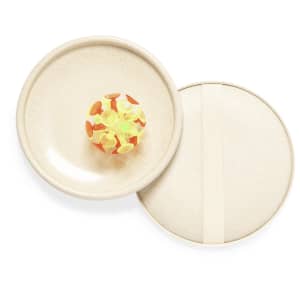 A round, light beige tray with a playful, colourful ball resting in the centre, featuring bright green and orange elements.