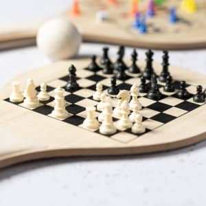 A wooden paddle featuring a chessboard design with black and white chess pieces on a black and white checkered background.