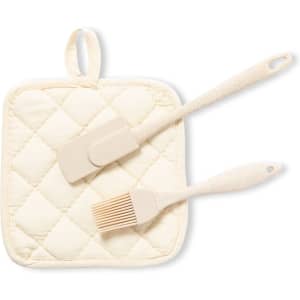 A cream-coloured quilted pot holder with a silicone spatula and a basting brush. The set has a simple design and a logo.