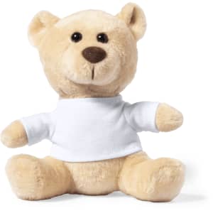 A soft, beige teddy bear wearing a plain white shirt, sitting upright with a friendly expression. It features a small logo.