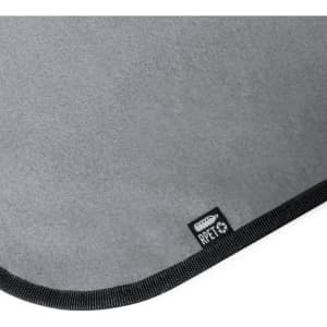 A grey picnic blanket with a textured surface and black edging, featuring a small logo.