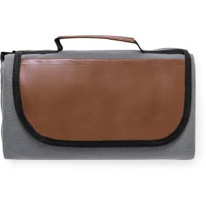 A grey picnic blanket with a brown leather flap and a handle for easy carrying. Features a logo on the front.