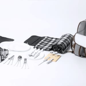A grey picnic cool bag backpack with checkered picnic blanket, plates, cutlery, and drink cups neatly arranged.