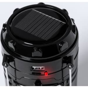 A black power bank lamp with a solar panel on top, featuring a USB port and an indicator light.