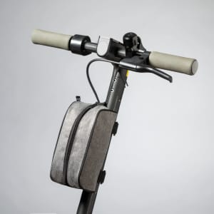 A grey scooter bag attached to the handlebar of a scooter, featuring a zip closure and a small strap.