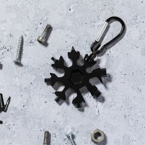 A black multitool keyring shaped like a snowflake, surrounded by screws and nuts, with a carabiner attached.