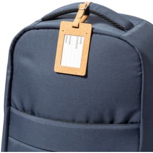 A blue backpack featuring a Natural-coloured luggage tag for personal details. The tag has a logo.