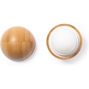 A circular lip balm with a textured wooden exterior and a smooth white balm inside, featuring a logo.