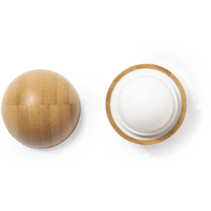A round lip balm with a textured bamboo-like exterior and a white balm interior. The product features branding.