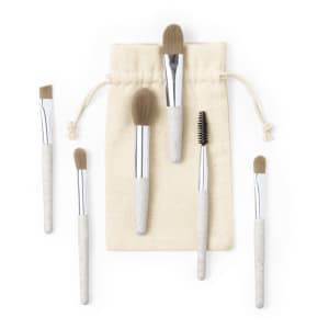 A set of six eyeshadow applicators with beige handles and silver ferrules, packaged in a cream-coloured drawstring bag.