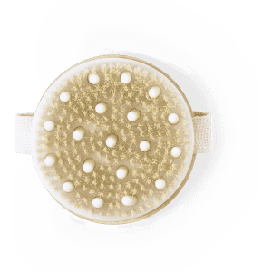 An exfoliating massage brush with a beige handle and textured bristles, featuring a strap for easy grip.