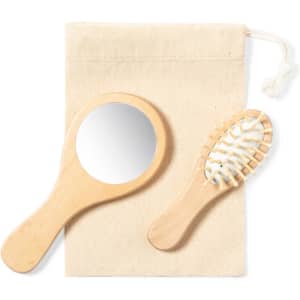 A wooden hand mirror and a hairbrush in a natural fabric pouch. Both items feature a light wood finish.
