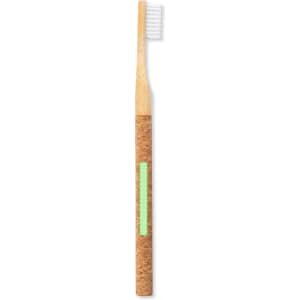 A bamboo toothbrush with a cork handle and white bristles, featuring a green accent. It has a logo on the handle.