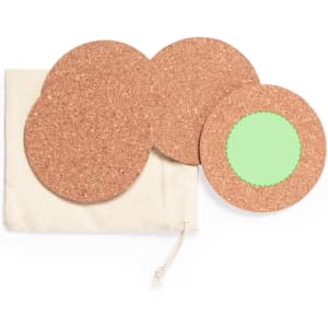 A set of four round cork coasters, one with a green centre, packaged in a cream drawstring bag.