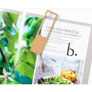 A magnifier bookmark in a natural beige colour, positioned in an open book featuring a salad recipe and green foliage.