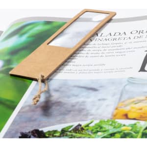 A magnifier bookmark made of brown cardstock with a transparent lens, placed on a magazine page.