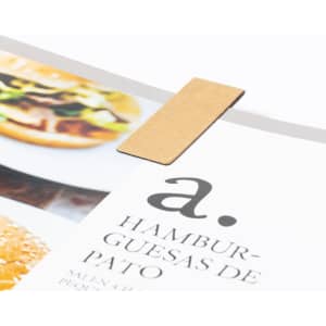 A magnetic bookmark in a light brown colour, holding a page in a magazine featuring food images.