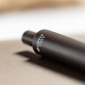 A black pen with a cylindrical body lying on a dark surface, featuring a logo on its side.