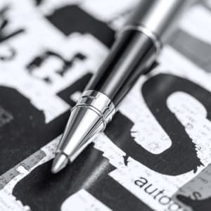 A metal pen with a sleek black and silver design resting on a textured surface featuring printed graphics.