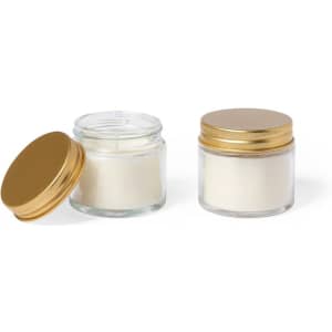 A set of two fragrant candles in glass jars with gold lids, one slightly open, featuring a creamy white hue.