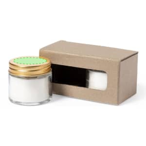 A glass candle jar with a gold lid, accompanied by a cardboard box with a window opening.