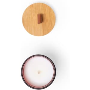 A round aromatic candle with a white wax interior and a wooden lid, featuring a dark container.