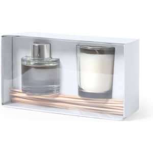 A transparent gift box containing a glass candle, a diffuser bottle, and wooden reed sticks.