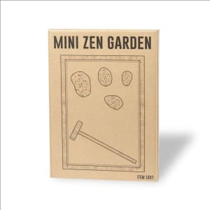 A mini zen garden kit in a cardboard box featuring a rake and stones, with a simple, minimalistic design.