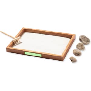 A mini Zen garden featuring a wooden tray, sand, a rake, and decorative rocks in natural tones.