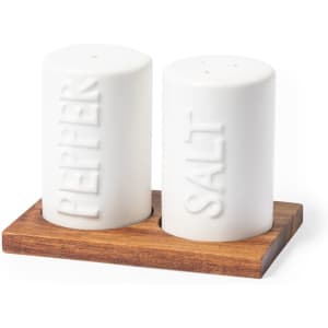 A white salt and pepper shaker set on a wooden tray with embossed labels.