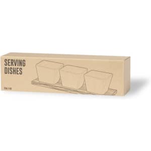 Three square serving dishes displayed in a cardboard box with a wooden base. The packaging features a simple line drawing.