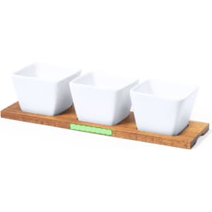 Three white ceramic serving dishes arranged on a wooden tray. The tray features a subtle green accent.