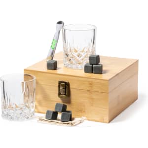 A whisky set featuring two crystal glasses, grey cooling stones, a pick, and a bamboo box.